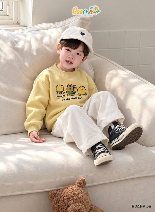 Bé mặc sweater doodle ngồi sofa